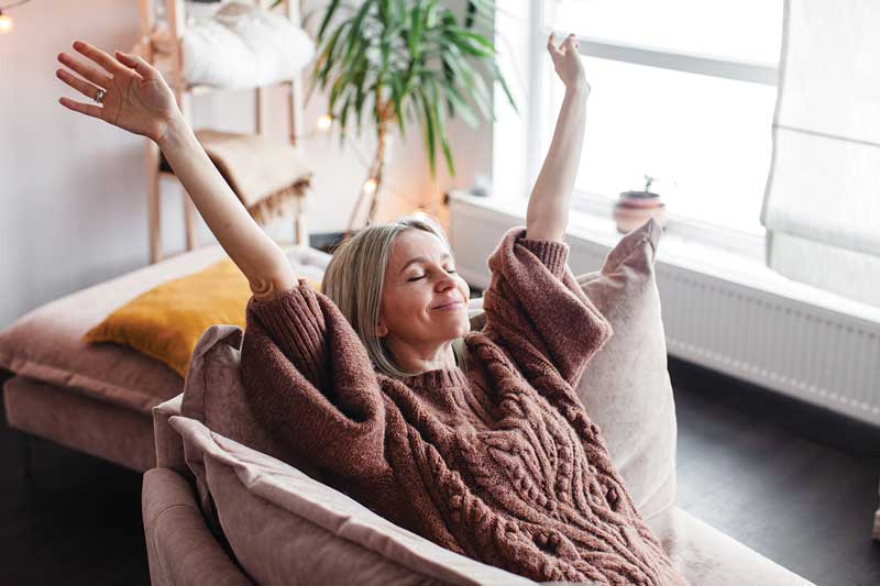 Woman stretching comfortably at home after improving her overall wellness